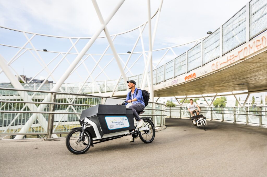 Zwei Lastenräder fahren um eine Kurve